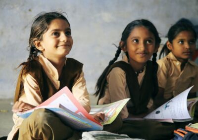 Three young Indian school pupils sitting on the floor with text books on their laps