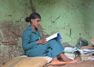 An Ethiopian grade 9 female student reading with a pile of books