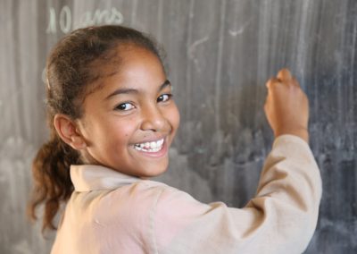 Smiling girl wriiting on a blackboard