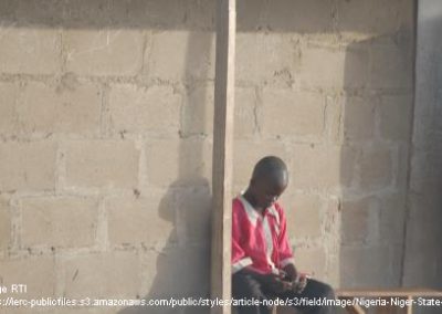 Nigerian boy sitting outside a building