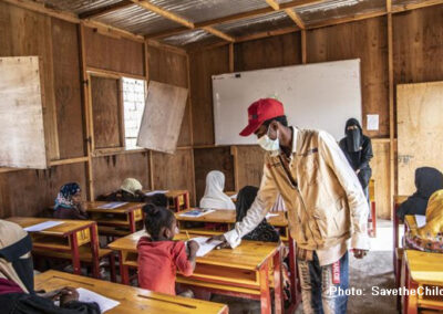 Masked teacher working with children in class