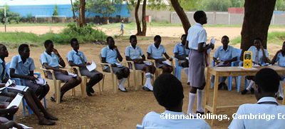 Outside classroom with students sitting on chars in circle around the teacher