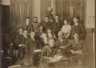 a sepia tinted photograph of students in period dress with women students among them