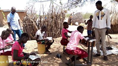 Outside classroom with teachers and students working at desks