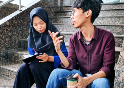 Two adult students in discussionm  sitting on steps 