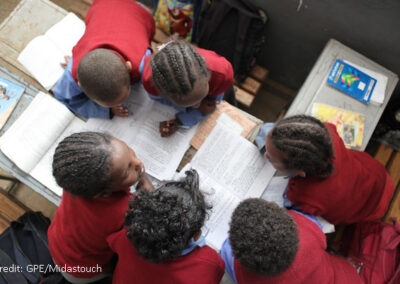 View from above of five children working on sheets and with textbooks in a classroom.