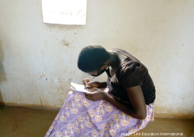 girl sitting writing, she is wearing a facemask