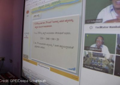 Photo of a computer screen with shared lesson and teacher and pupil with headsets and mics