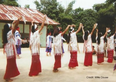 Women dancing in a village location wearing traditional dress