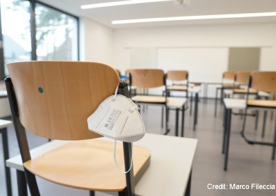 Face mask hanging off the back of a chair in an empty classroom