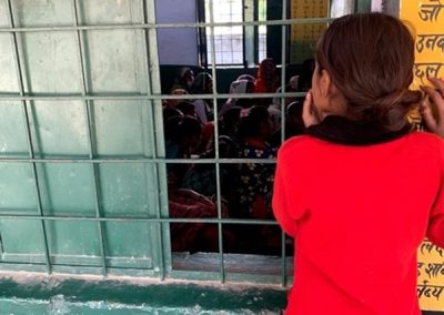 A girl curiously listening to interactions between mothers and teacher, from outside the room, at a school in Sitapur, India.