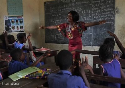 female teacher laughing with children in the classroom, Sierra Leone