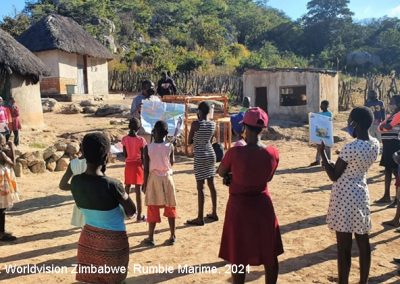 Teaching volunteer holds an informal community learning circle class outside in a rural village with social distancing and masks, Zimbabwe.