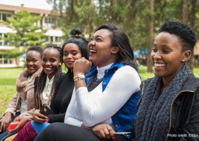 Group of young women laughing on a bench outside their university.