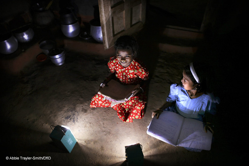 Two girls study by solar light at night in Tinginaput, rural Orissa, India