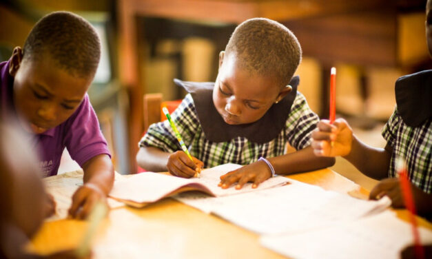 Young children learn writing at their desk in a primary school, Ghana.