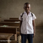 Young boy stands next to his desk on his first day back to school.