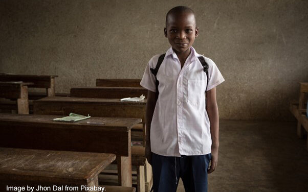 Young boy stands next to his desk on his first day back to school.