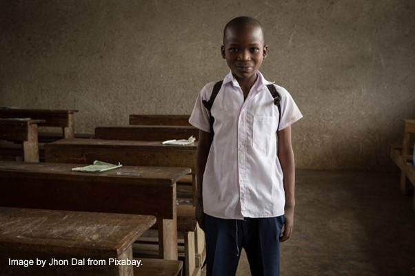 Young boy stands next to his desk on his first day back to school.