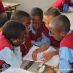 Students wearing blue and red uniform in class 4C at the Hidassie Primary School in Addis Ababa, Ethiopia, do group work during a social science class.