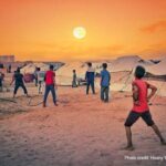 A group of boys play football next to their tents in the sunset, Gaza Strip.