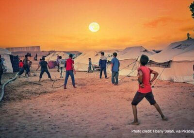 A group of boys play football next to their tents in the sunset, Gaza Strip.