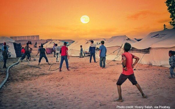 A group of boys play football next to their tents in the sunset, Gaza Strip.