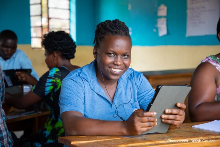 Teacher wearing a blue shirt, trying out a tablet through the STELIR project, Rwanda