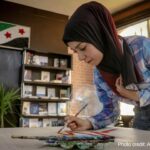 Woman painting on a table in a library, Aleppo