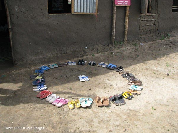 Shoes in a circle outside school with one pair in the middle. Students and teacher leave their shoes outside the door to keep the class clean. Gudele West Basic School, outside Juba, South Sudan.