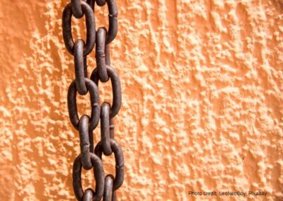 Rusty chains hang against an orange painted wall.