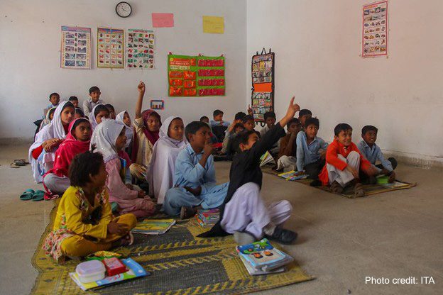 Pre-primary school students sit on mats on the floor of an early childhood education class in Punjab, Pakistan