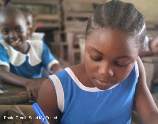 Girl dressed in blue writes in classroom.