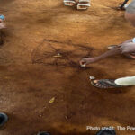 Parents draw on the ground while playing a traditional game.